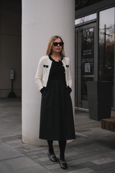 a lady in a white cardigan with black trim and a black dress